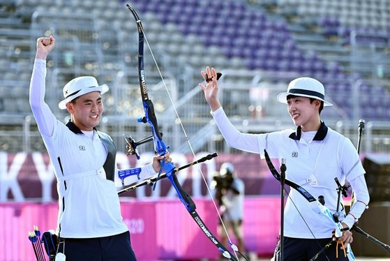 图为7月24日，韩国射箭代表队的金济德(左)和安山在日本东京梦之岛公园射箭场管举行的东京奥运会射箭混合团体赛决赛中获得金牌后，正在高兴地进行庆祝。东京=奥运会联合摄影记者团V